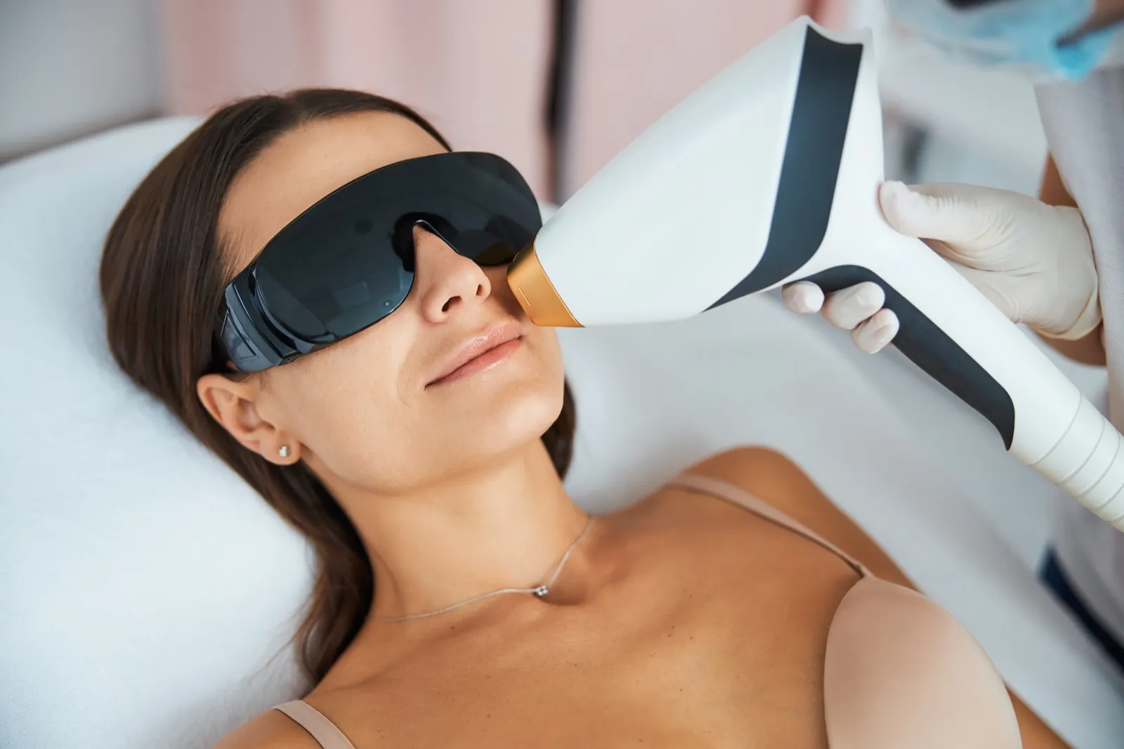 Kundin mit Schutzbrille bei der Laser-Haarentfernung im Gesicht