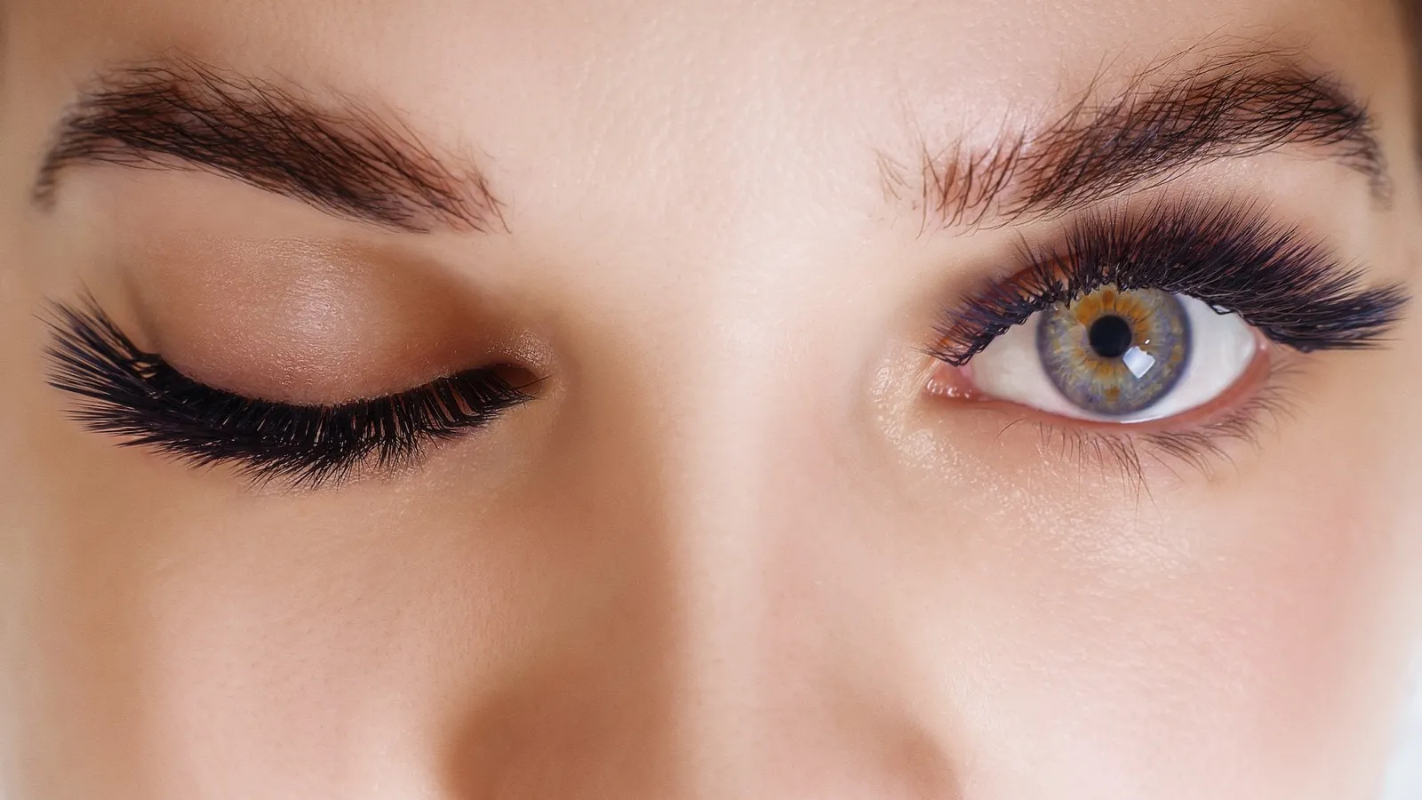 Augenpartie mit verlängerten Wimpern, ein Auge geschlossen, eines offen